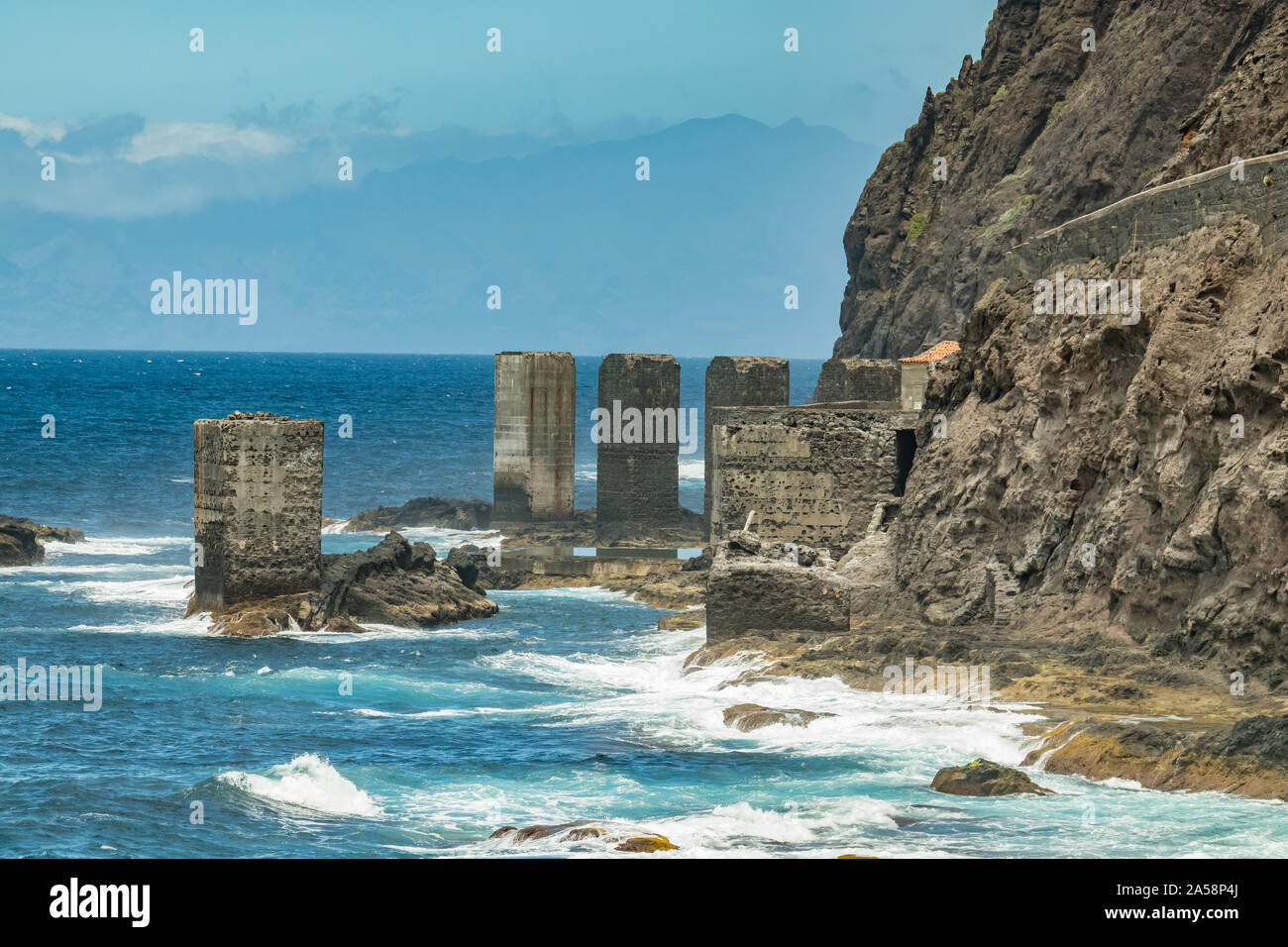 Vista dell'isola di Tenerife da Santa Catalina beach. Enormi pilastri di calcestruzzo per gru e le rovine della vecchia Hermigua porta. La Gomera Canarie, Isla Foto Stock