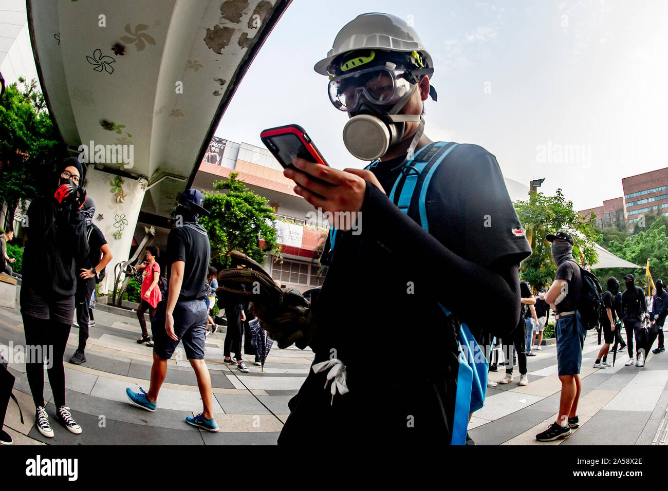 A Hong Kong protestor indossa una maschera a gas controlla il suo telefono per le strade di Hong Kong Foto Stock