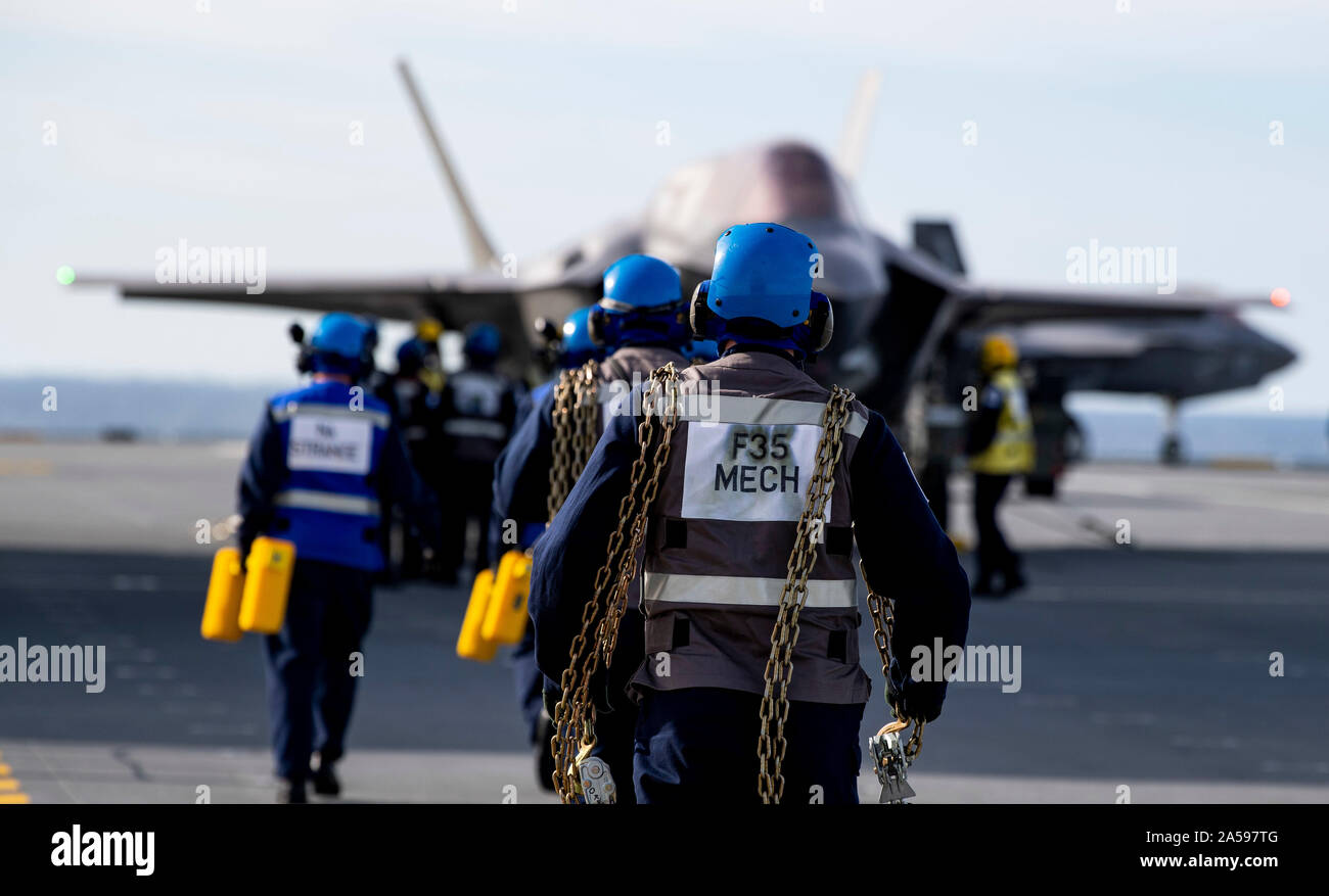 191017-N-QI061-1340 OCEANO ATLANTICO (ottobre, 17, 2019) velisti assegnati per HMS Queen Elizabeth (RO 8) portare catene in tutto il ponte di volo durante le operazioni di volo nell'Oceano Atlantico. HMS Queen Elizabeth è attualmente implementata in supporto di WESTLANT 19 che implica la pianificazione di missione, armare il velivolo utilizzando la nave è altamente automatizzato di arma sistema di movimentazione, battenti missioni e debriefing sul completamento. Il primo spiegamento operativo per HMS Queen Elizabeth 617 Squadrone e uno squadrone di US Marine Corps Lightning getti si terrà nel 2021. (U.S. Navy foto di comunicazione di massa S Foto Stock