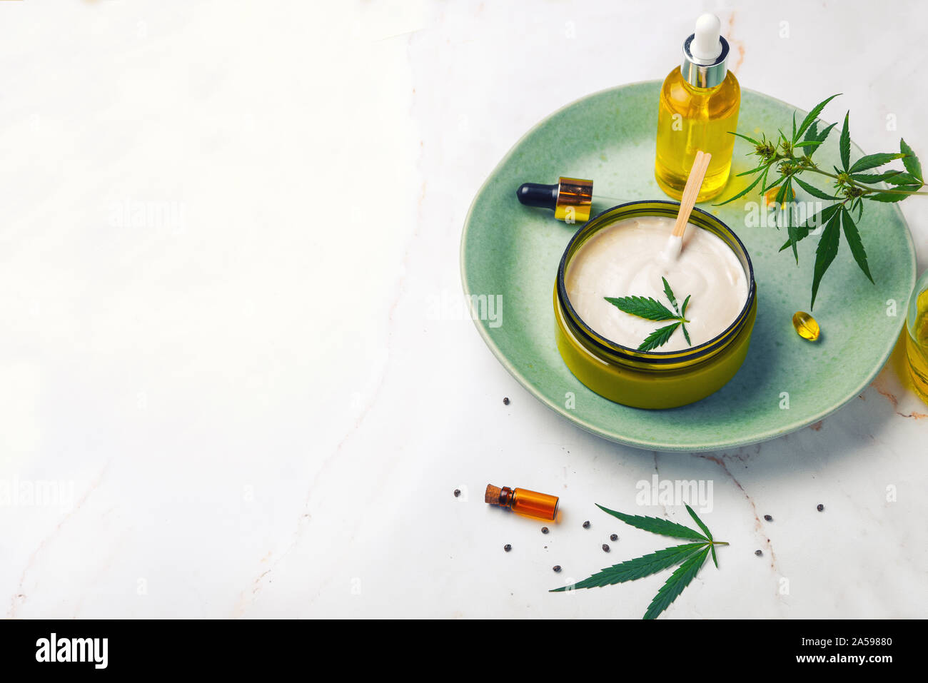 Banca di crema medicinale con olio di CBD, una bottiglia di olio di cannabis, capsule, su una piastra verde. Appartamento laico, vista dall'alto. Cannabidiolo CBD bottiglie di oli di canapa Foto Stock