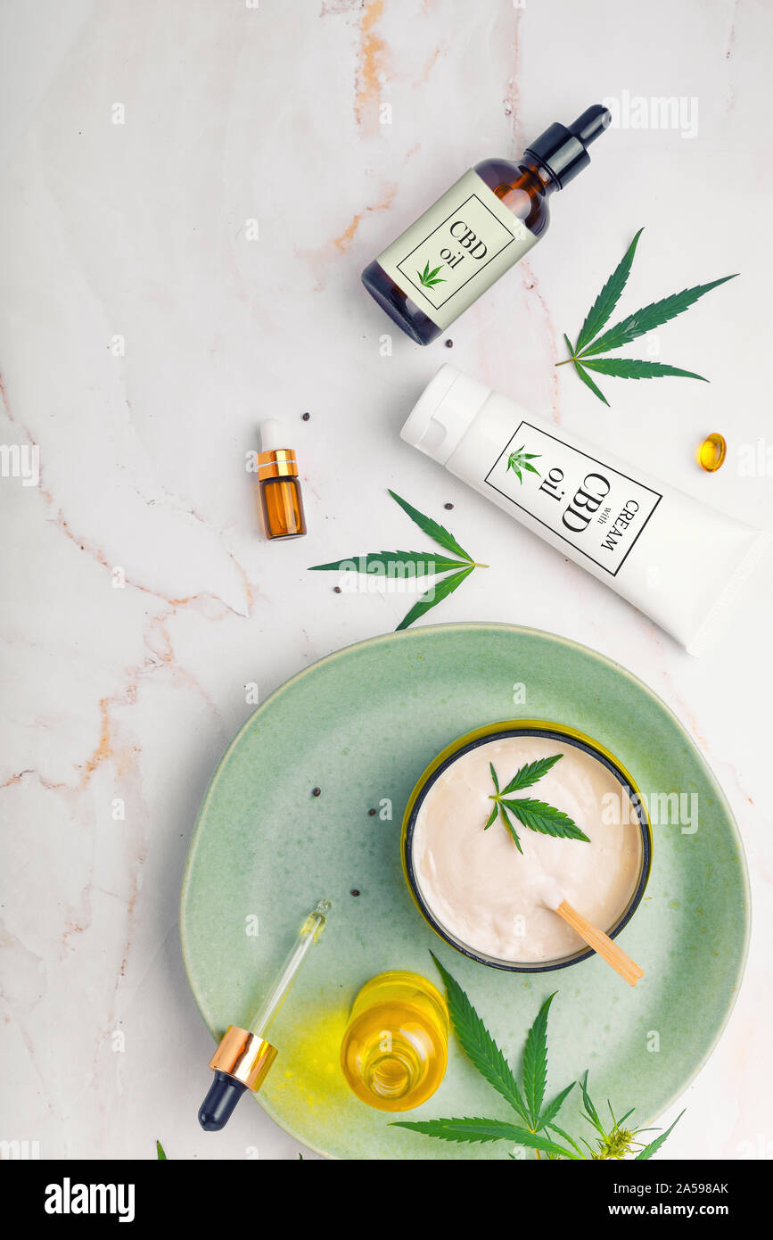 Cosmetici con olio di cannabis su un turchese piastra su una luce Sfondo marmo. Concetto di lusso per la cura della pelle. Foto Stock