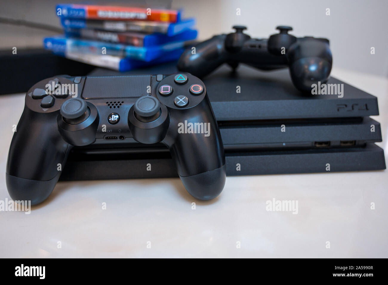 Sony Play Station 4 pro gaming console sul tavolo con due joystick e alcuni  giochi su DVD per PS4 Foto stock - Alamy