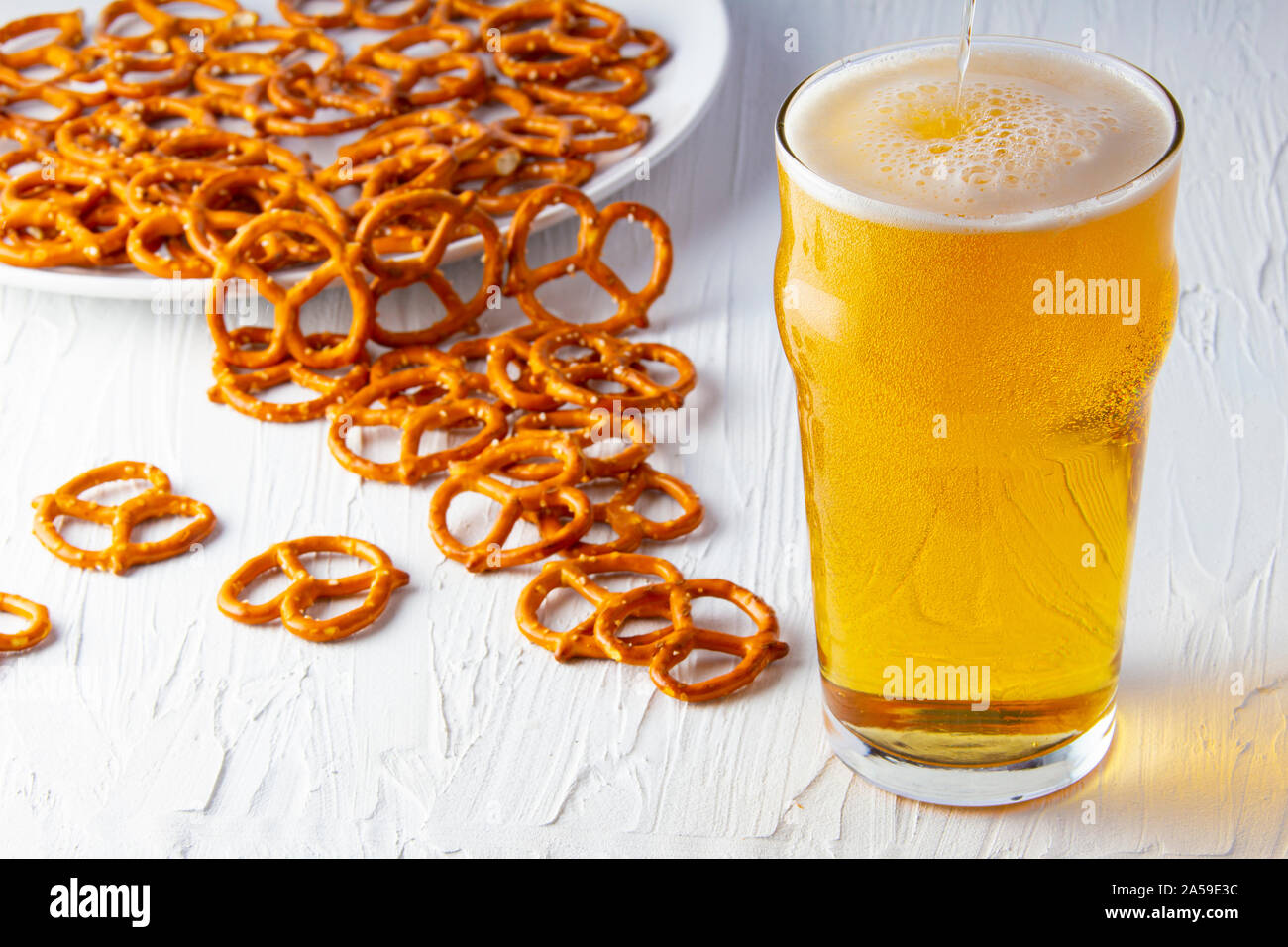 Birra e salatini su sfondo bianco Foto Stock