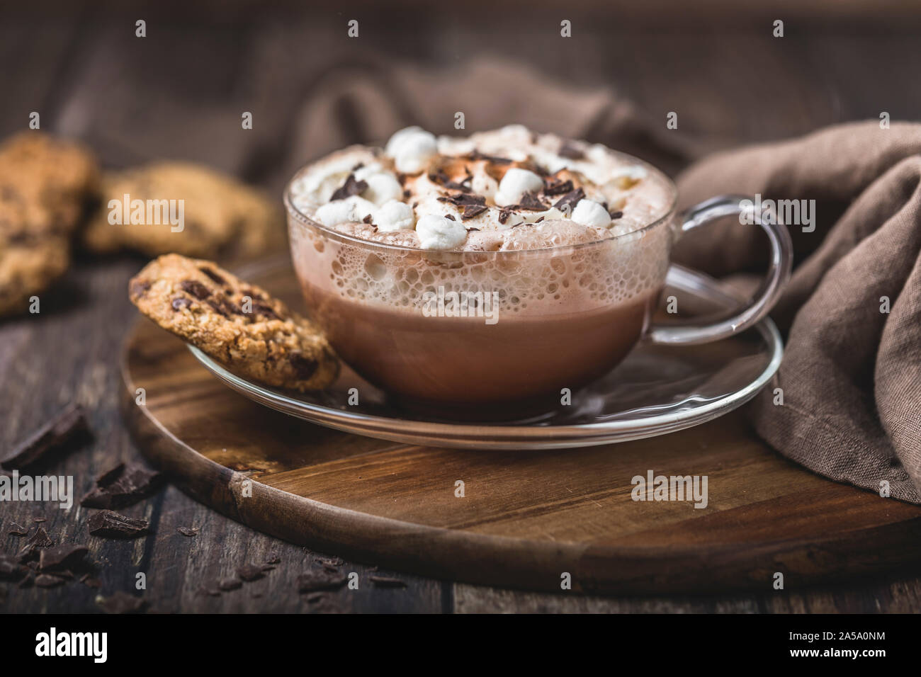 Cioccolata calda con panna montata in un bicchiere di vetro su un vetro piattino. Il cioccolato viene cosparsa con un po' di cioccolato fondente grattugiato. Ci sono alcuni chocola Foto Stock