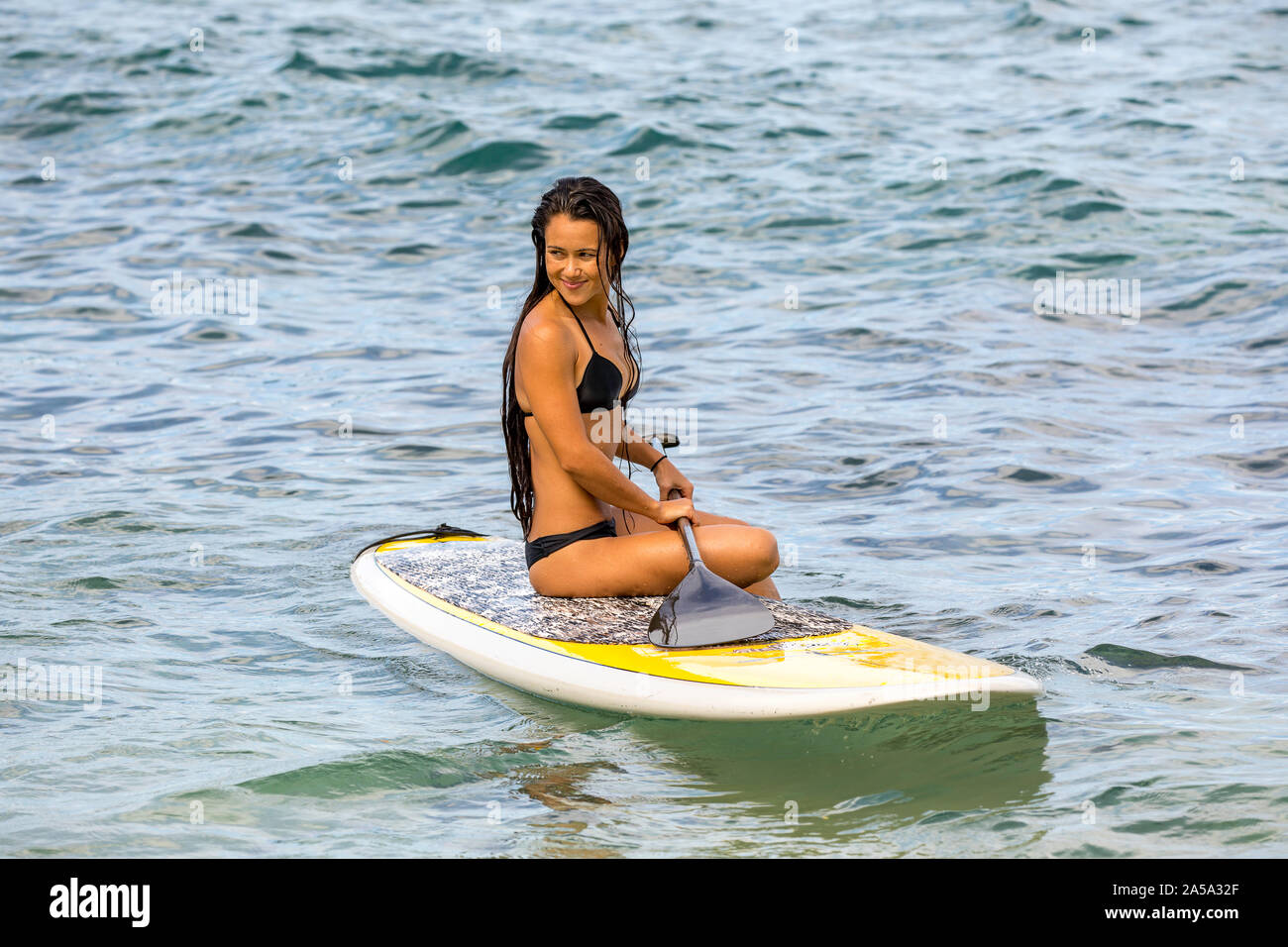 Una ragazza seduta su uno stand up paddle board, Hawaii. Questa fotografia è il modello rilasciato. Foto Stock