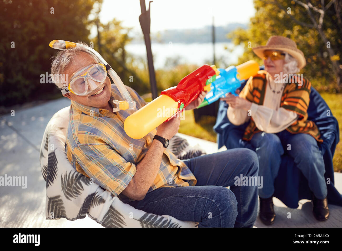 Sorridente coppia Senior in vacanza giocando con la pistola ad acqua Foto Stock