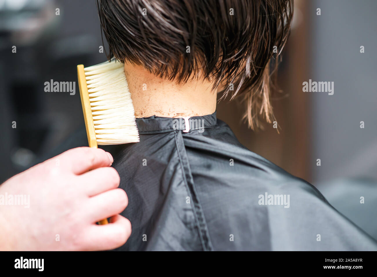 Parrucchiere scuote i capelli tagliati dal collo della donna al salone di parrucchiere. Barbiere uomo è la pulizia i capelli tagliati dal collo della donna nel salone di bellezza. Taglio di capelli al salone. Foto Stock