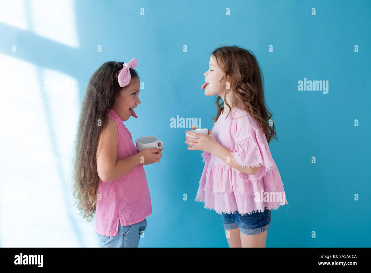 Due bambine mostrano la lingua l'una all'altra Foto Stock