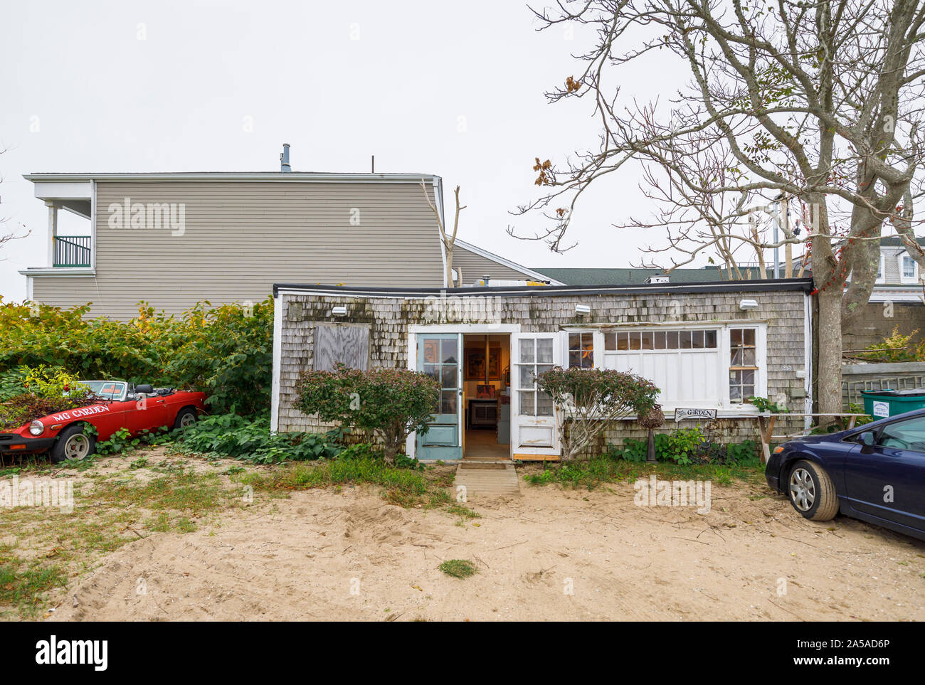 Vintage auto MG con piante che crescono dal motore sulla spiaggia al di fuori di un fatiscente art gallery in a Provincetown (P-città), Cape Cod, New England, STATI UNITI D'AMERICA Foto Stock