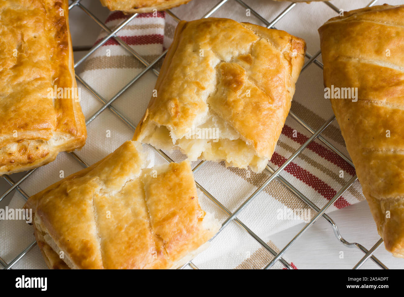 Formaggi saporiti e cipolla pasta sfoglia panini freschi di forno raffreddamento su una cottura trivet un vegetariano alternativa al solito rotolo di salsiccia Foto Stock