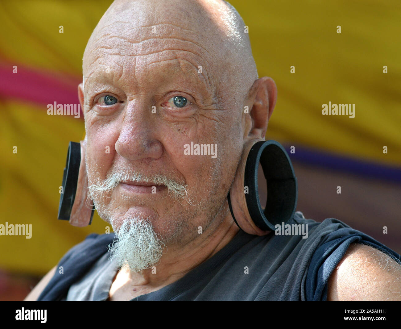 Anziani uomo caucasico (expat) con grandi orecchioni allungato pone per la fotocamera a Bangkok. Foto Stock