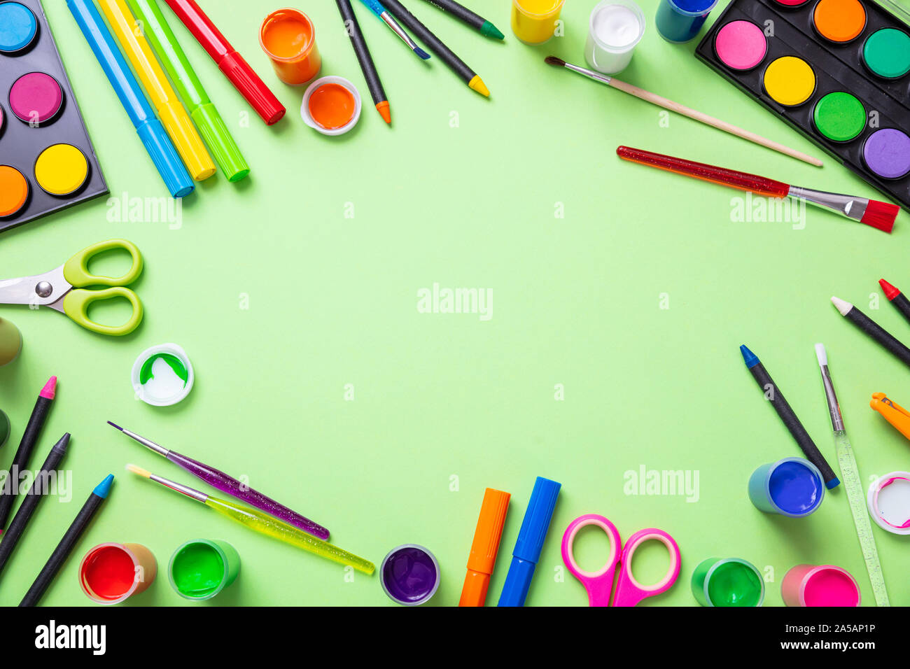 I bambini la creatività. Vernici colorate e pennelli flat giaceva sul verde pastello colore di sfondo, vista dall'alto, spazio di copia Foto Stock