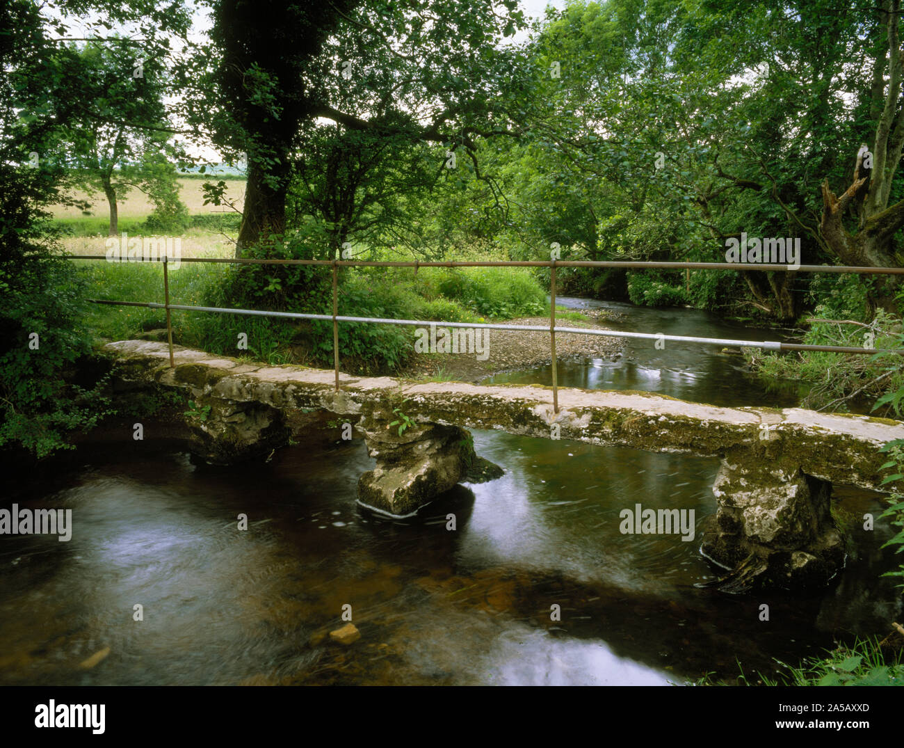 Llanarmon Yn Ial passerella sul fiume Alyn. Claper ponte di lunga e stretta di lastre di pietra supportato su pietra grezza e piloni in cemento con corrimano in ferro Foto Stock