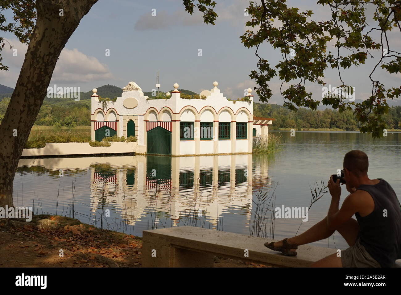 L'uomo prendendo foto di bella casa galleggiante sul lago di Banyoles Foto Stock