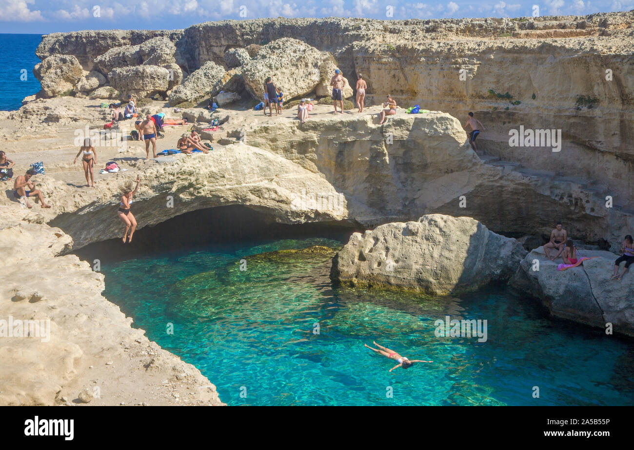 Donna che si tuffa nella caverna di poesia, una famosa piscina naturale, Roca Vecchia, Melendugno, Lecce, Puglia, Italia Foto Stock