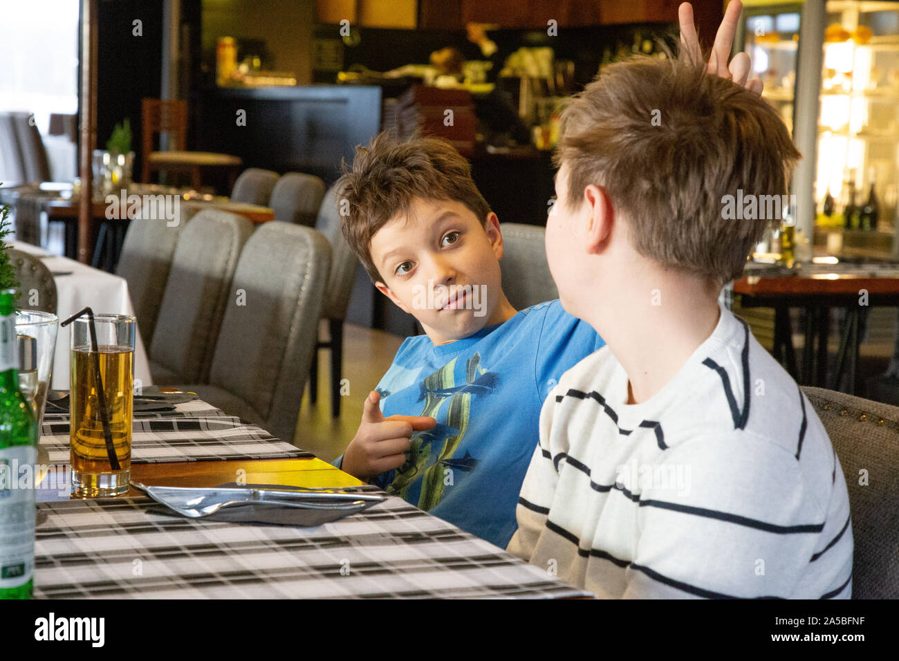 Due ragazzi in attesa per la pizza in un ristorante. - I fratelli avendo  divertimento Foto stock - Alamy