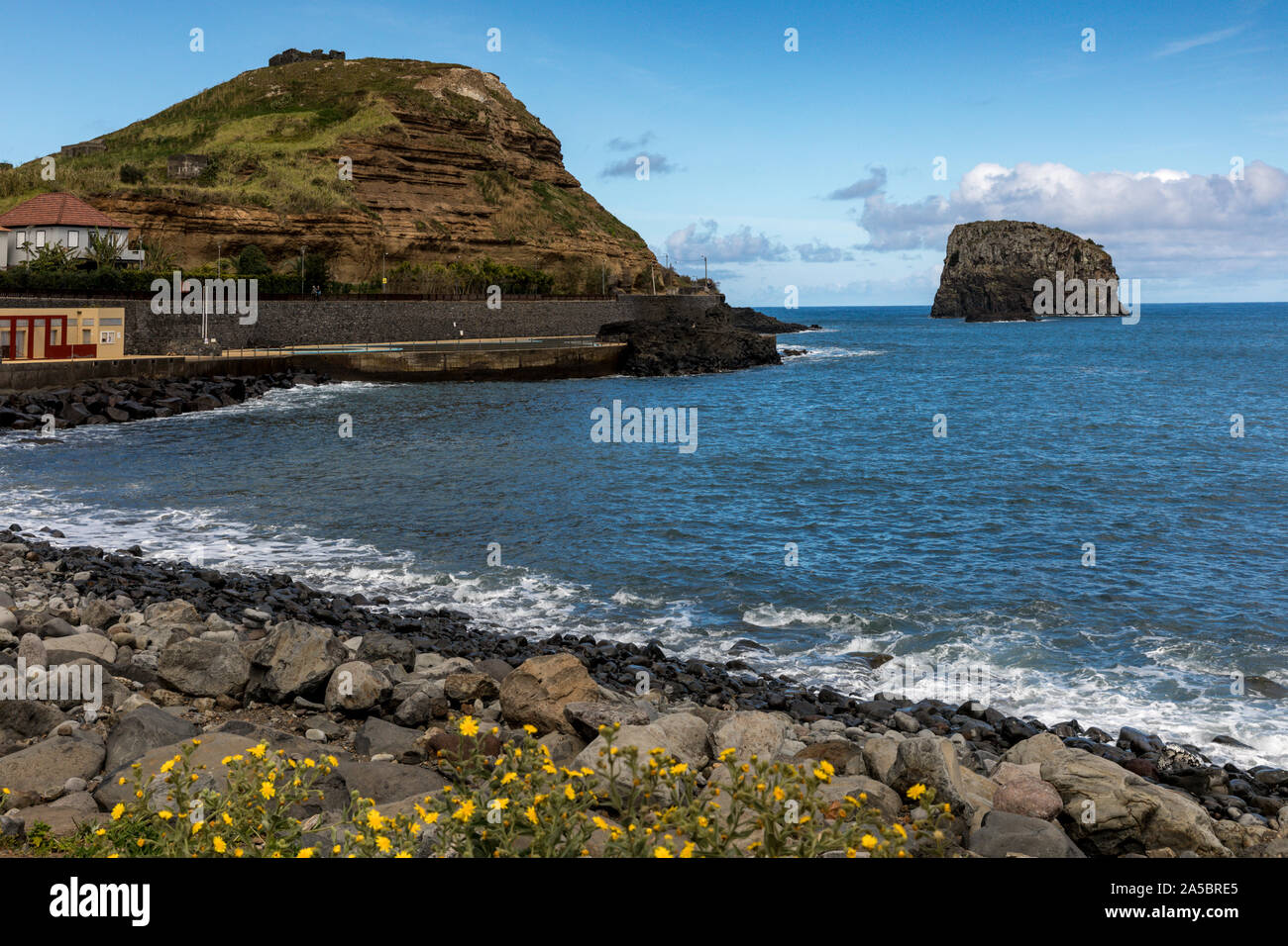 Spiaggia, costa e parete del mare a Porto da Cruz, Madeira, Portogallo. Il paese è dominato dal massiccio faccia a strapiombo di Eagle Rock a nord. Foto Stock