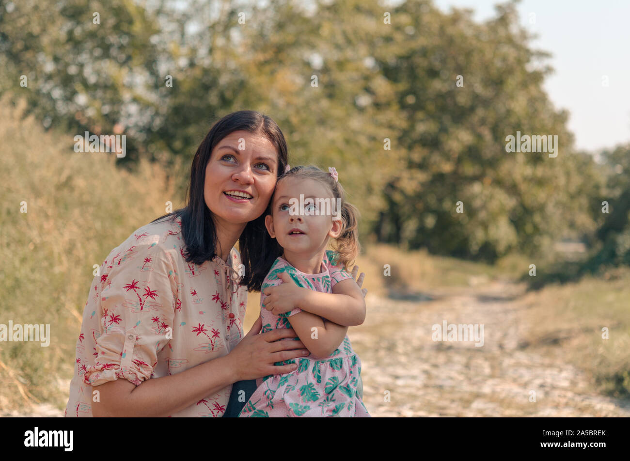 Adorabili ragazze ridono per esterni. Foto di allegro caucasici madre e figlia con uno splendido sorriso. Donna e bambina di guardare in alto. Foto Stock