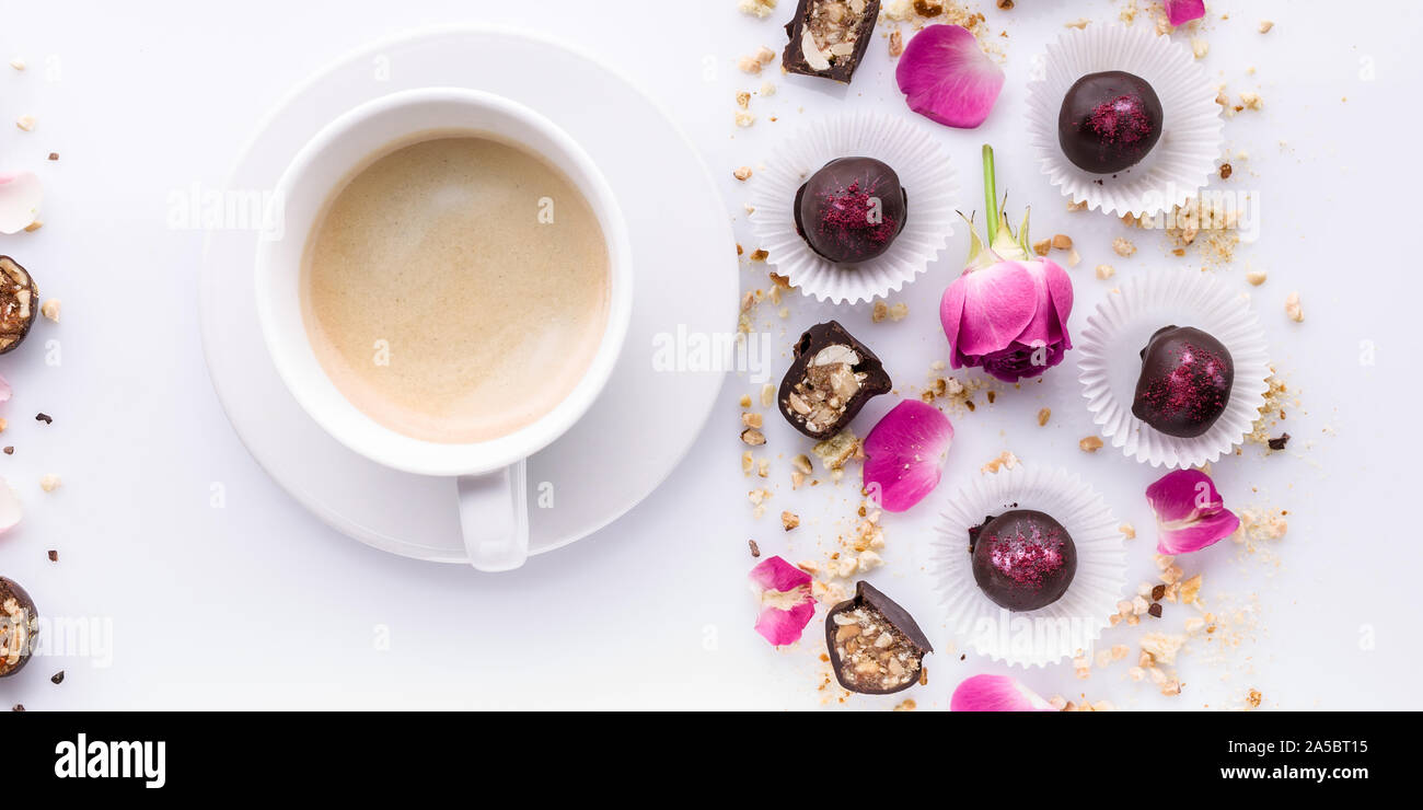 Banner di cibo. Bianco di ceramica tazza di caffè e cioccolatini fatti a mano con i dadi su uno sfondo bianco. Foto Stock