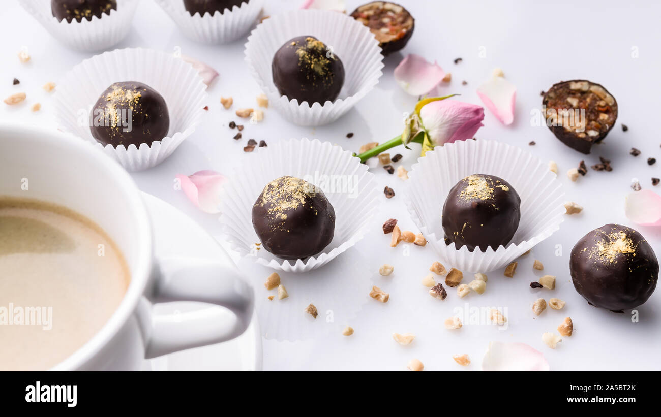 Banner di cibo. Bianco di ceramica tazza di caffè e cioccolatini fatti a mano con i dadi su uno sfondo bianco. Foto Stock