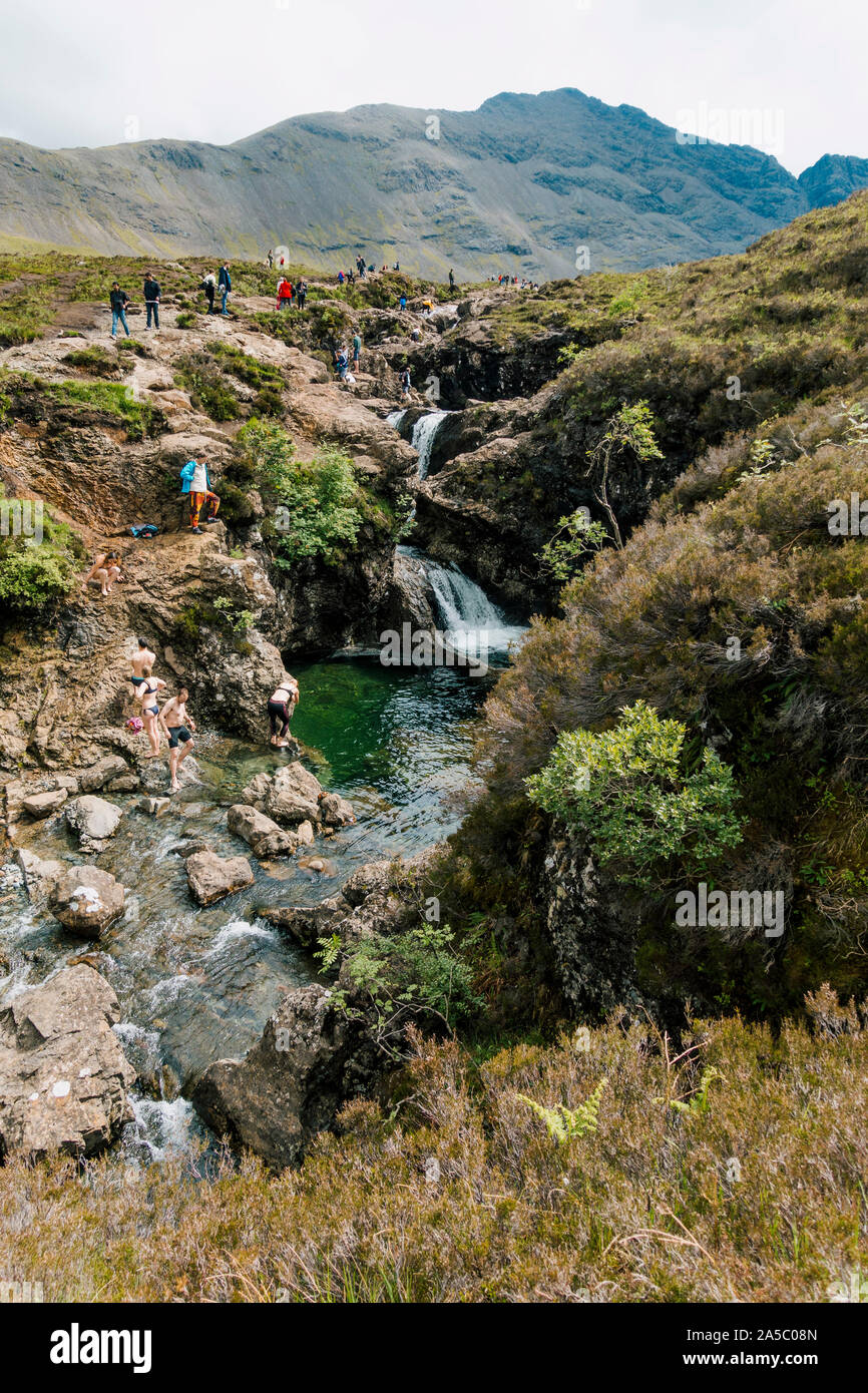 I turisti nuotare e scavalcare le cascate e rocce alla fata piscine, una famosa attrazione turistica dell'Isola di Skye in Scozia Foto Stock