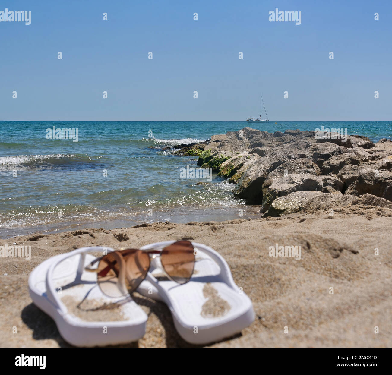 Piccola nave sulla spiaggia con il bianco pantofole e bicchieri al di fuori della messa a fuoco. Concetto di fine settimana Foto Stock