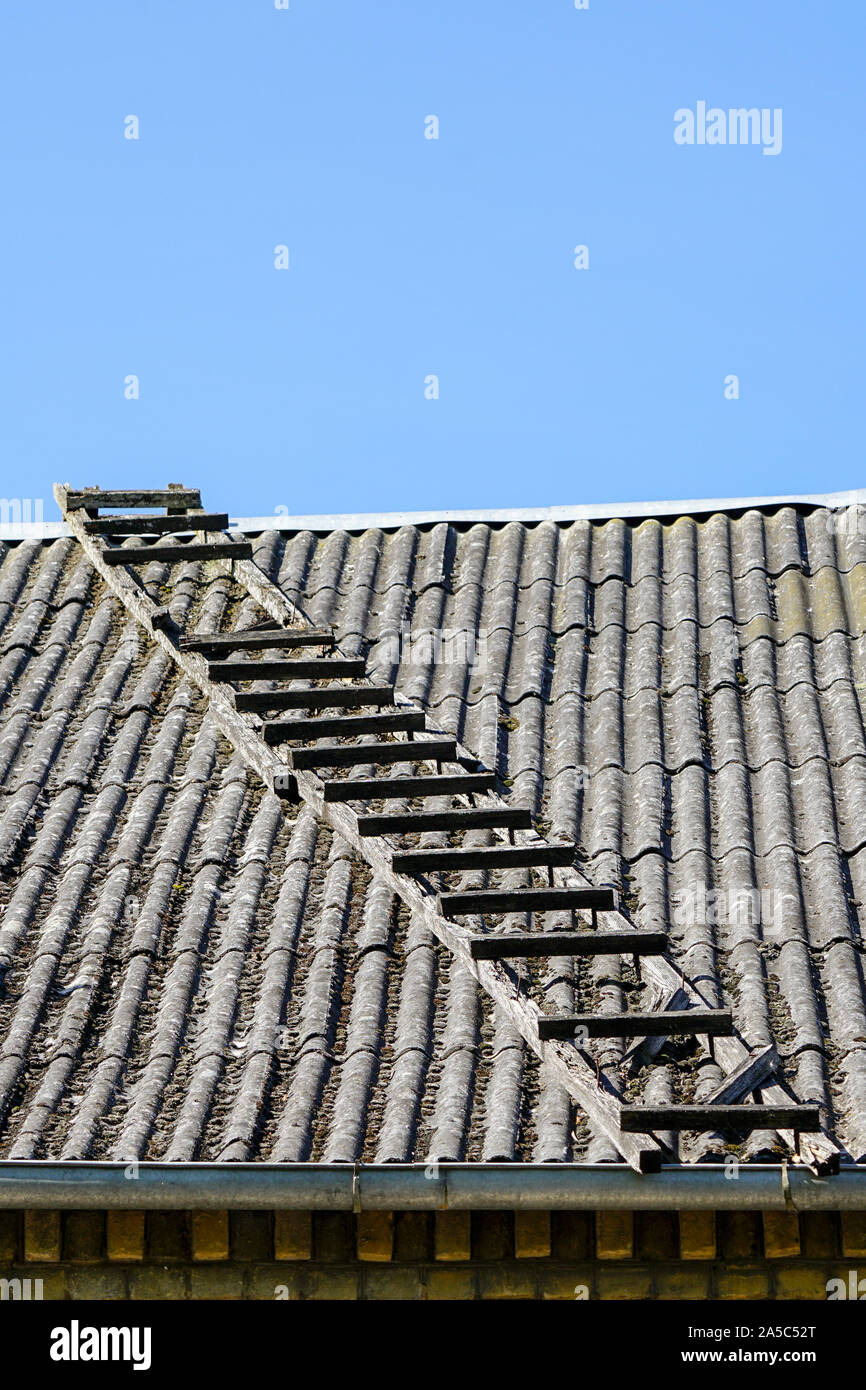 Vecchia scala di legno sul tetto in ardesia con cielo blu in background Foto Stock