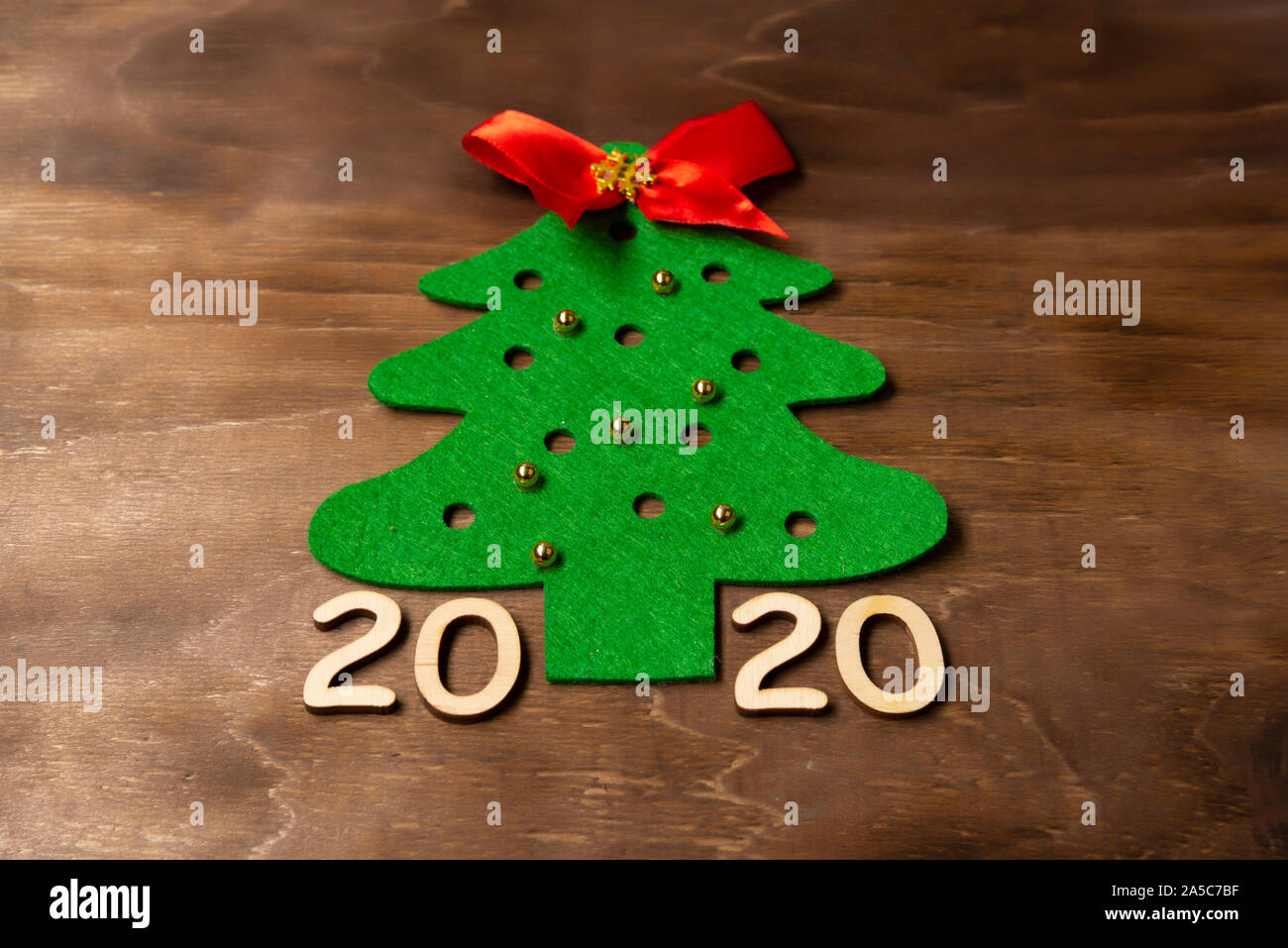 Albero di natale con un feltro giocattoli in legno scuro dello sfondo con i numeri 2020 Foto Stock