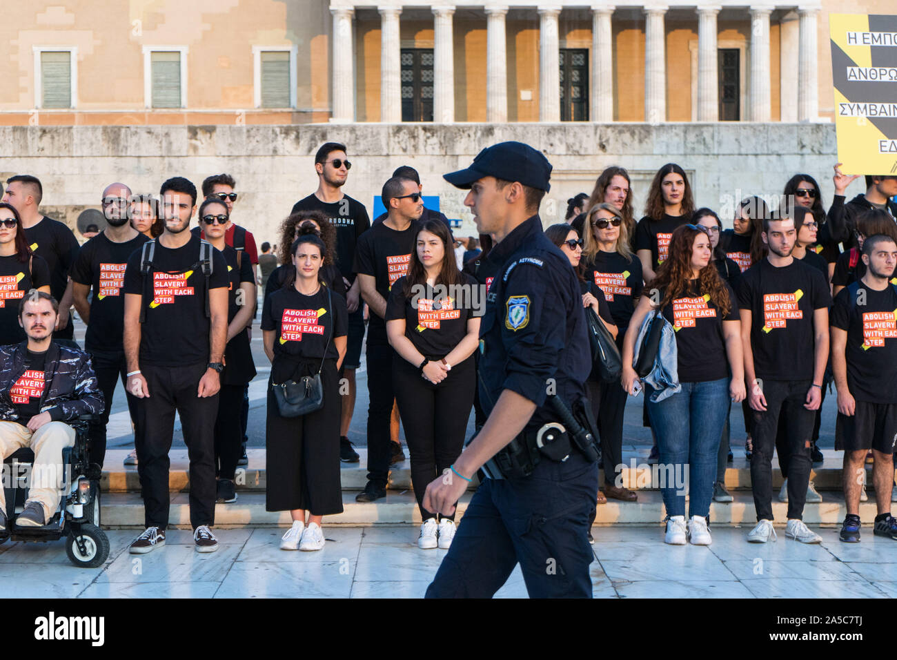Un funzionario di polizia passa di fronte ai partecipanti permanente al parlamento greco durante la sfilata.A piedi per la libertà è una risposta globale per il traffico di esseri umani. Si tratta di una presa di coscienza e di evento di beneficenza mobilitare migliaia di abolizionisti, tenendo milioni di passi in centinaia di città di tutto il mondo. Foto Stock