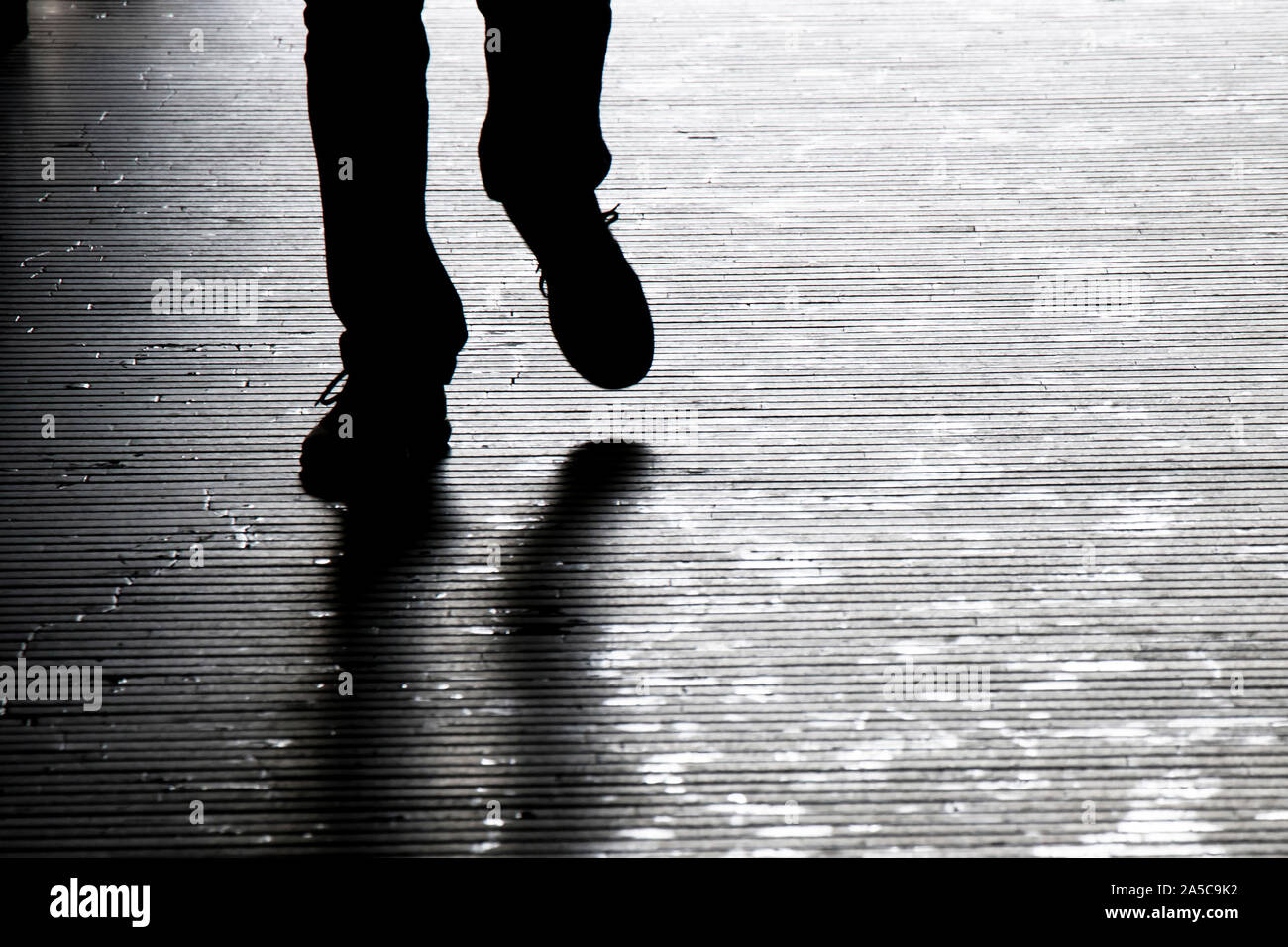 Sfocata ombra silhouette di un uomo che cammina nella notte, dettaglio delle gambe Foto Stock