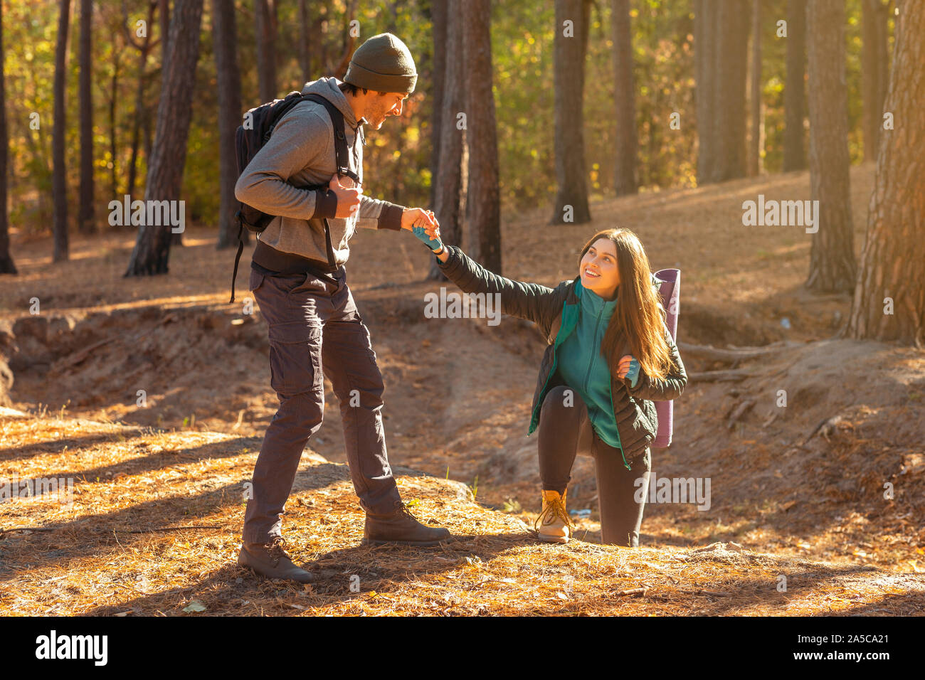 Bello escursionista aiutare la sua ragazza in salita in campagna Foto Stock