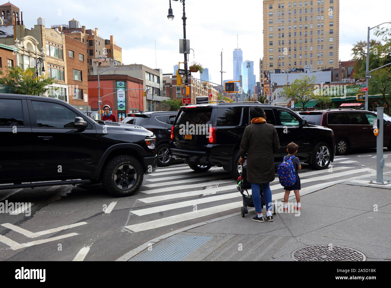 I driver di NYC in grandi vetture e SUV blocco a crosswalk pedonale e pista ciclabile evitando che una persona con un passeggino e bambini di attraversare in modo sicuro Foto Stock