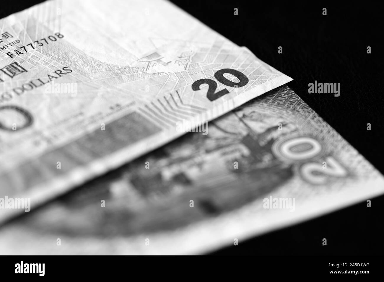 Due banconote di venti dollari di Hong Kong su uno sfondo scuro di close-up. In bianco e nero Foto Stock