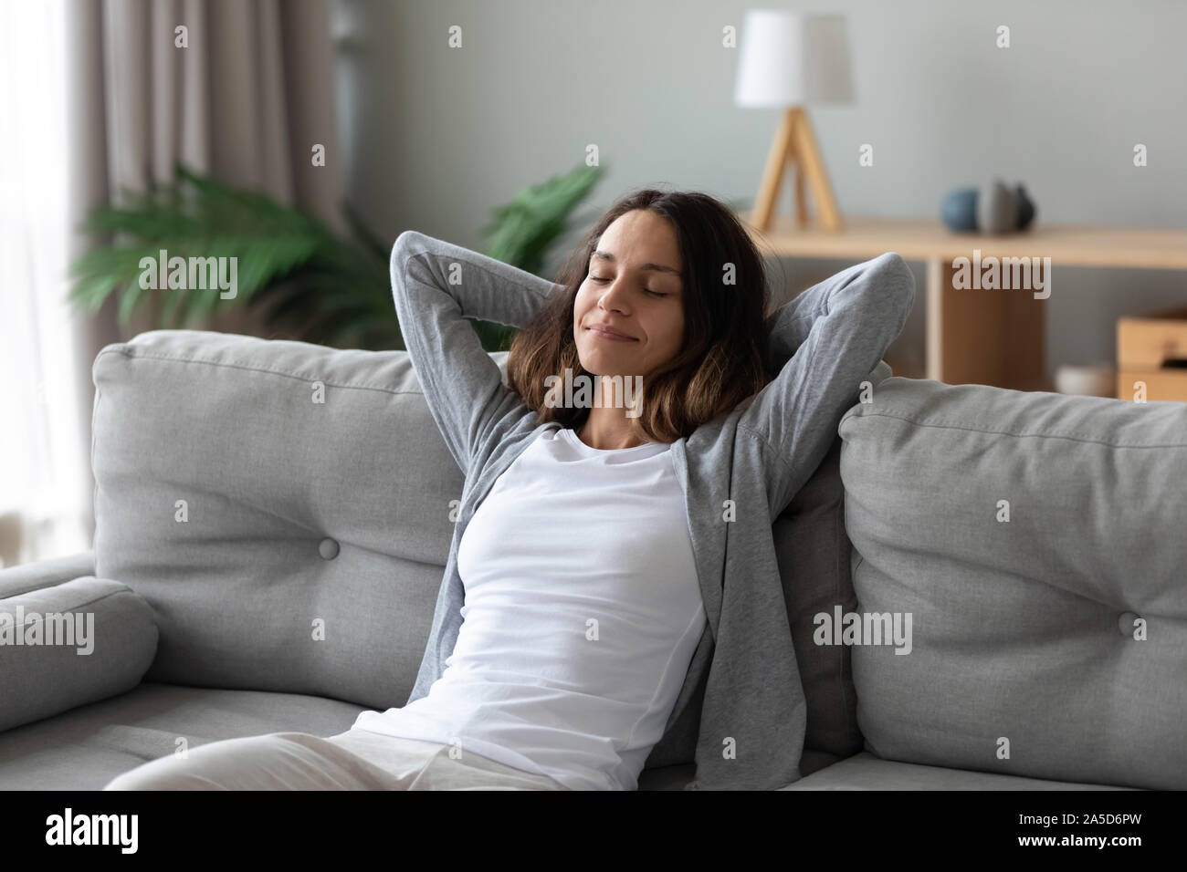 Tranquilla biracial sorridente donna millenario appoggiata sul divano. Foto Stock