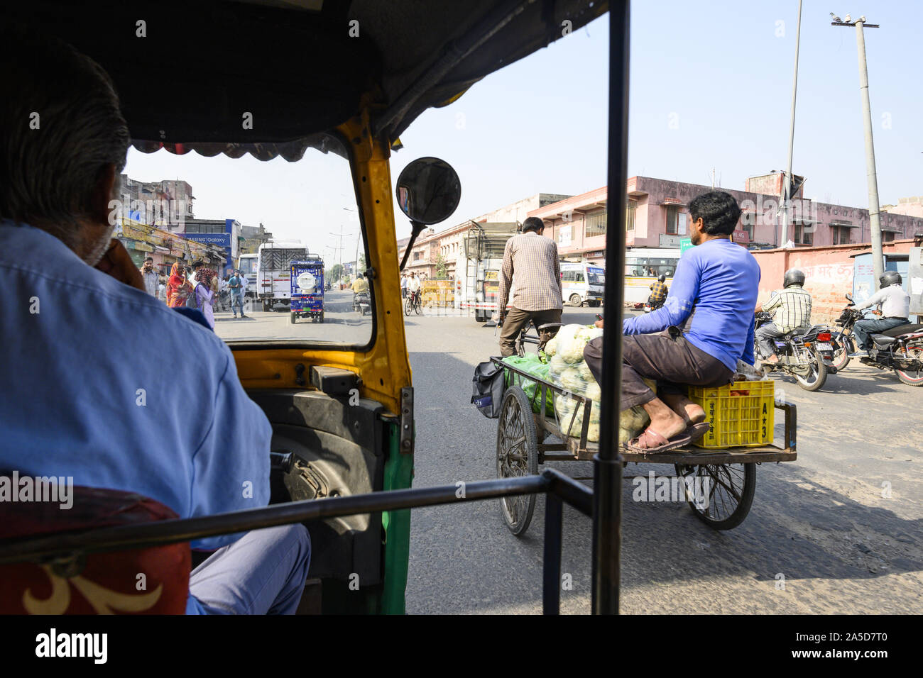 Un driver non identificato è a cavallo di un auto rickshaw attraverso le strade affollate di Jaipur. Foto Stock