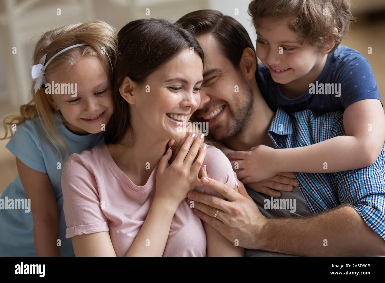 La famiglia felice godendo di momento di gara, i genitori e i bambini avvolgente Foto Stock