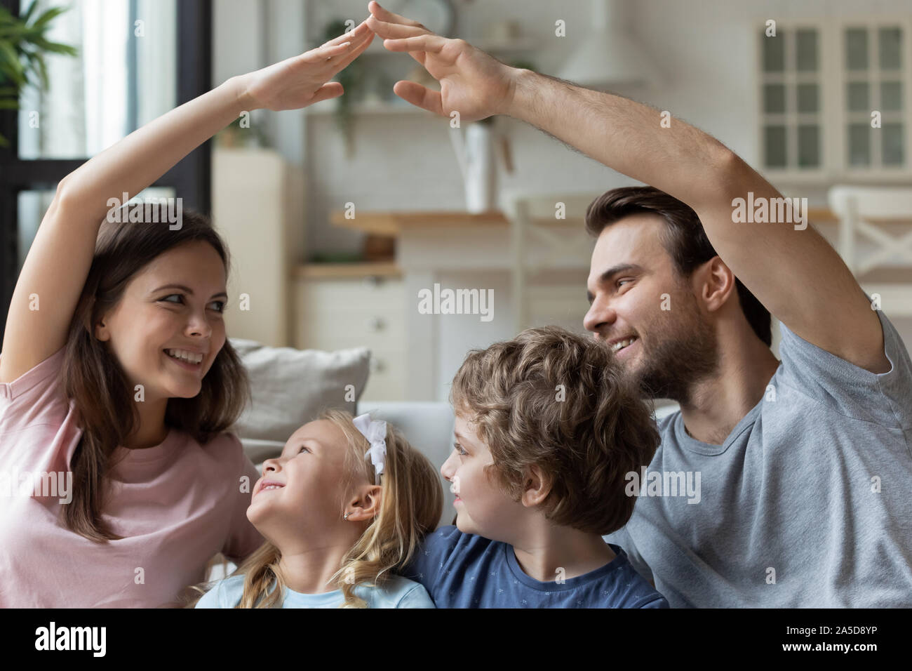 Sorridente seduta i genitori con bambini, rendendo il tetto gesti con le mani Foto Stock