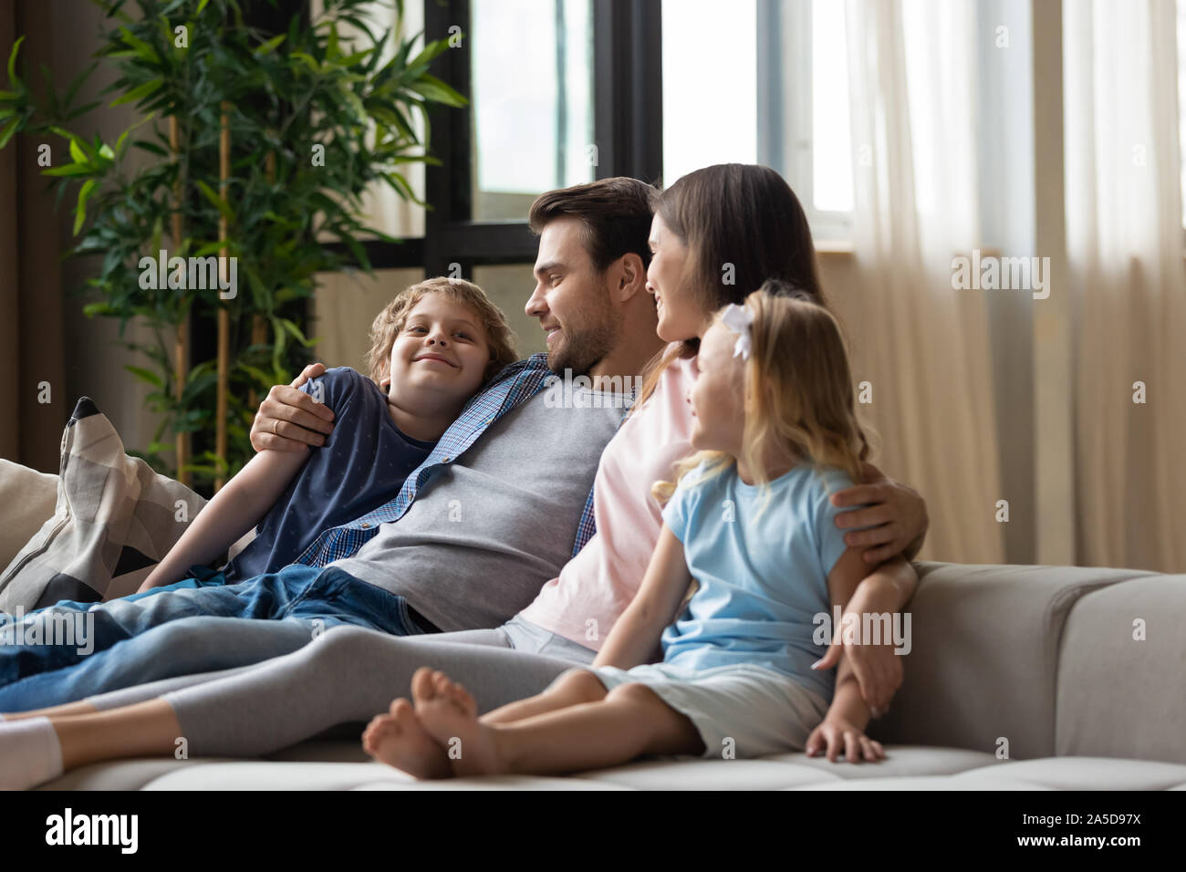 La famiglia felice, padre, madre e figli che abbraccia, rilassante sul lettino Foto Stock