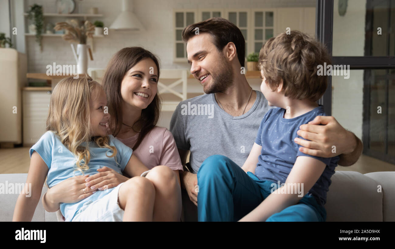 Sorridendo Il padre e la madre con i bambini seduti sul lettino Foto Stock