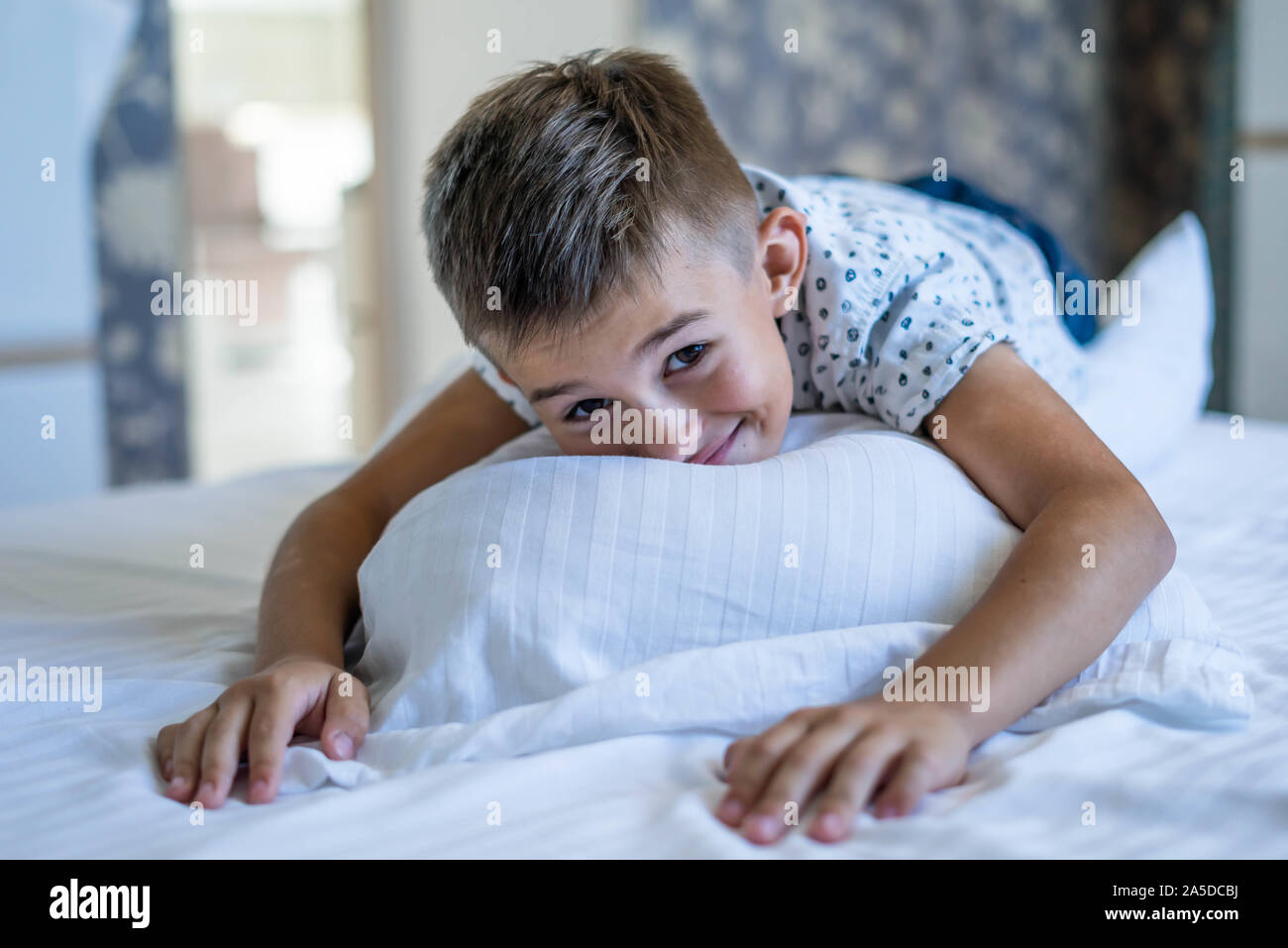 6 anni vecchio ragazzo disteso sul cuscino e sorridente Foto Stock