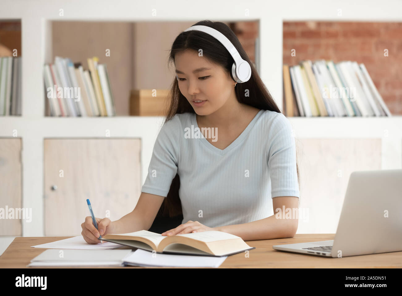 Studente asiatica ragazza che indossa le cuffie studio utilizzando il computer Foto Stock