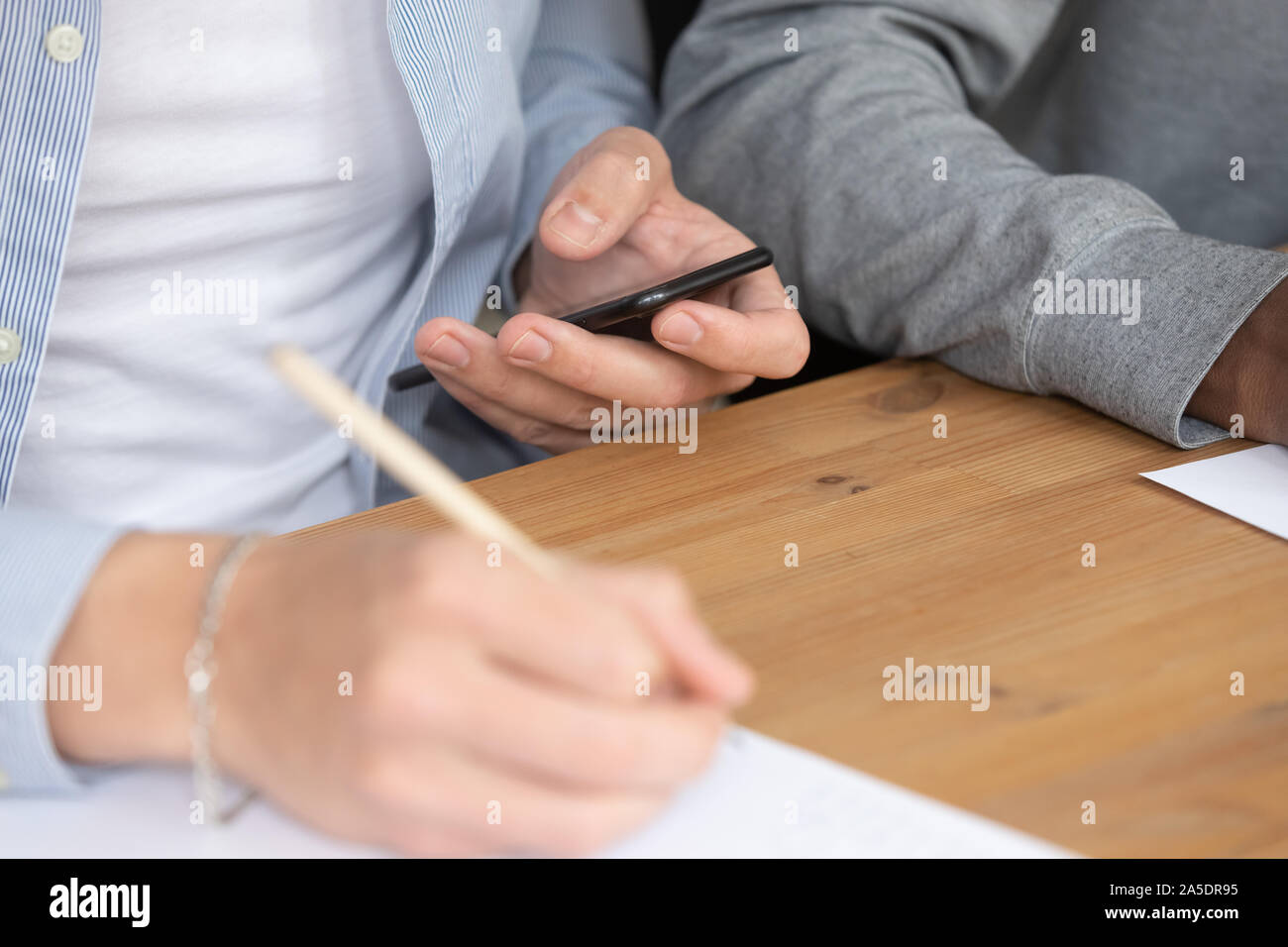Guy studiando la scrittura info leggere sullo smartphone utilizzando un sito web educativo Foto Stock