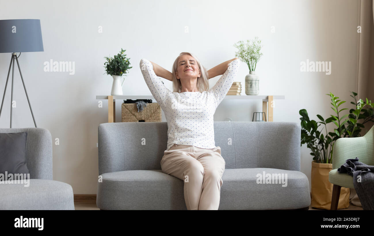 Felice donna di mezza età in appoggio sul divano con gli occhi chiusi Foto Stock