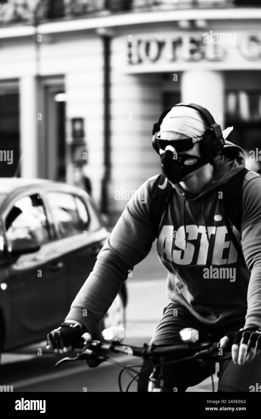 Foto in bianco e nero di un giovane uomo con maschera su una bicicletta per le strade di Bucarest, Romania, 2019 Foto Stock