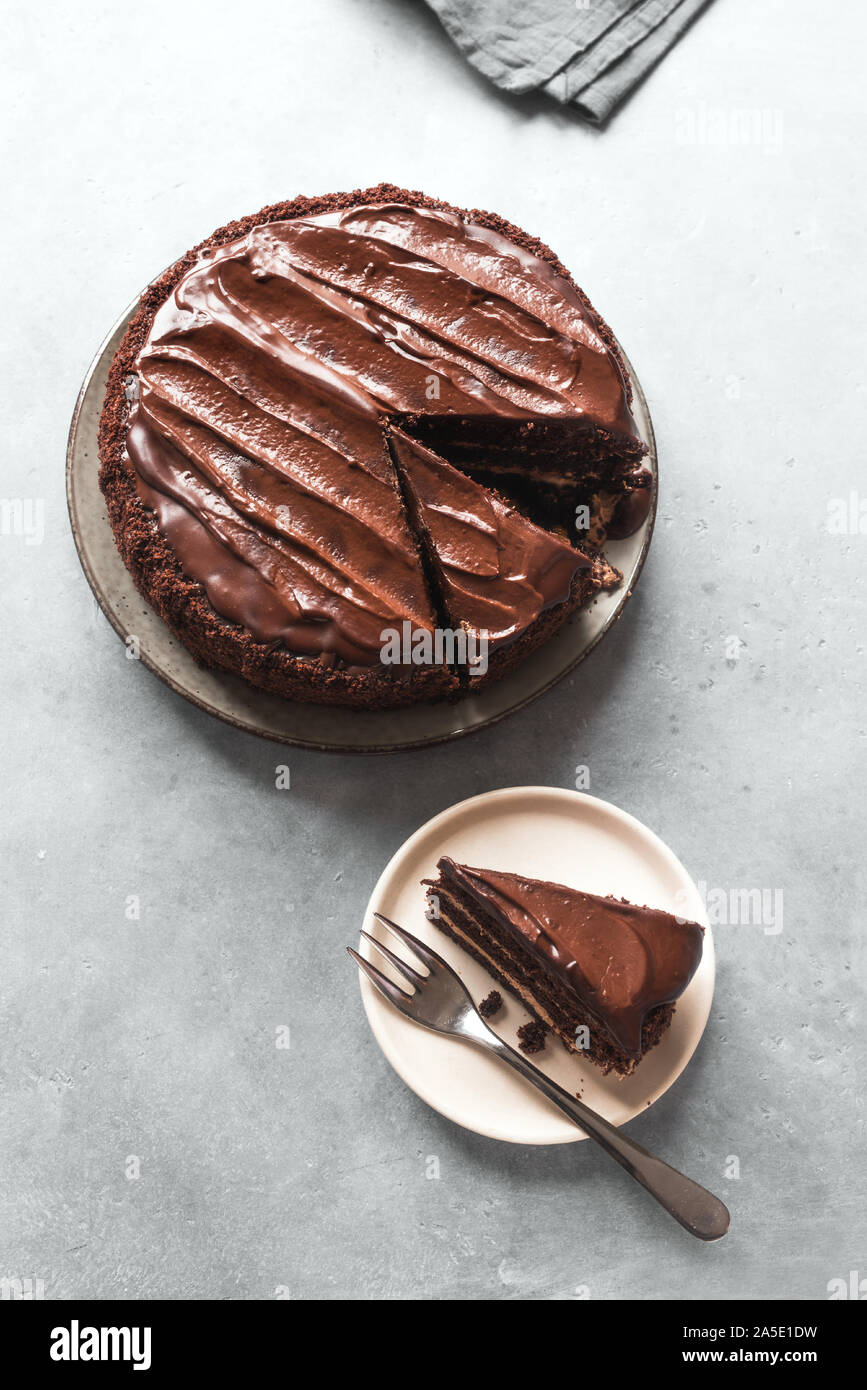 Torta al cioccolato con pezzi tagliati su sfondo grigio chiaro, vista dall'alto, copia dello spazio. Classica torta al cioccolato con cioccolato fondente ganache. Foto Stock