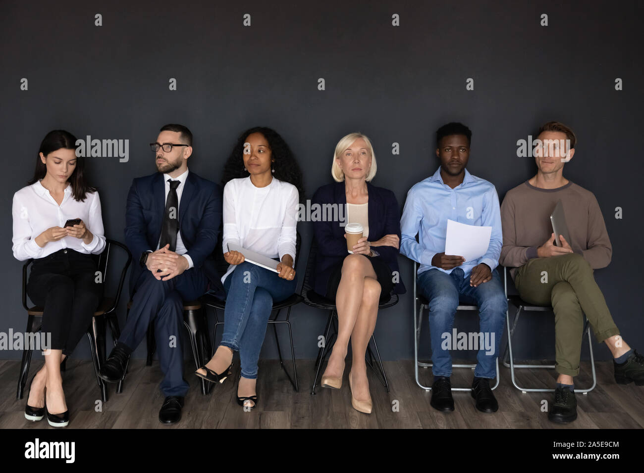 Grave ha sottolineato diversi imprenditori sedere sulle sedie in attesa il colloquio di lavoro Foto Stock