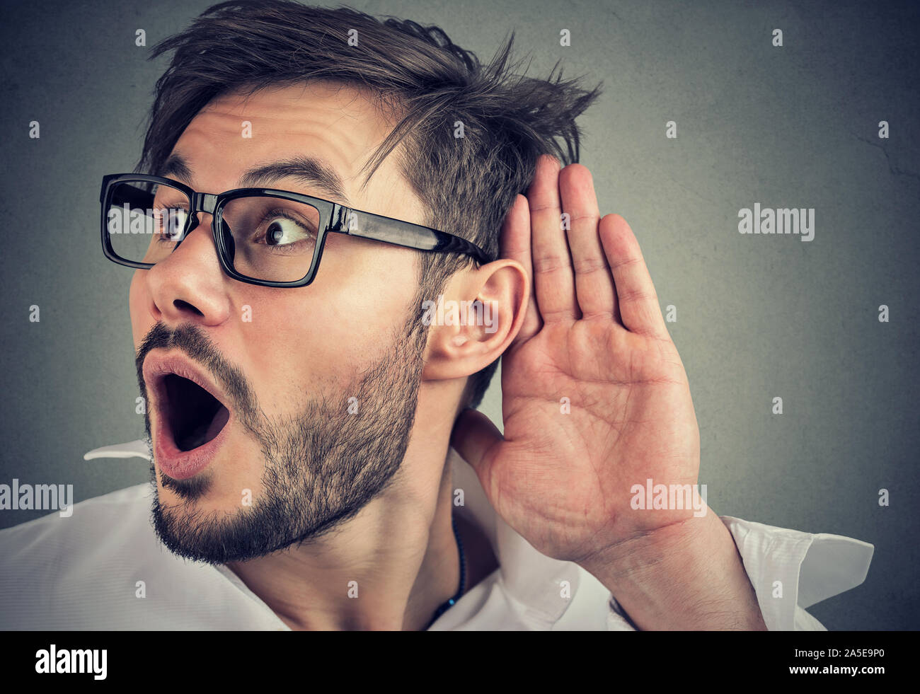 Primo piano di una scioccato simpatiche uomo segretamente in ascolto sulla conversazione privata Foto Stock