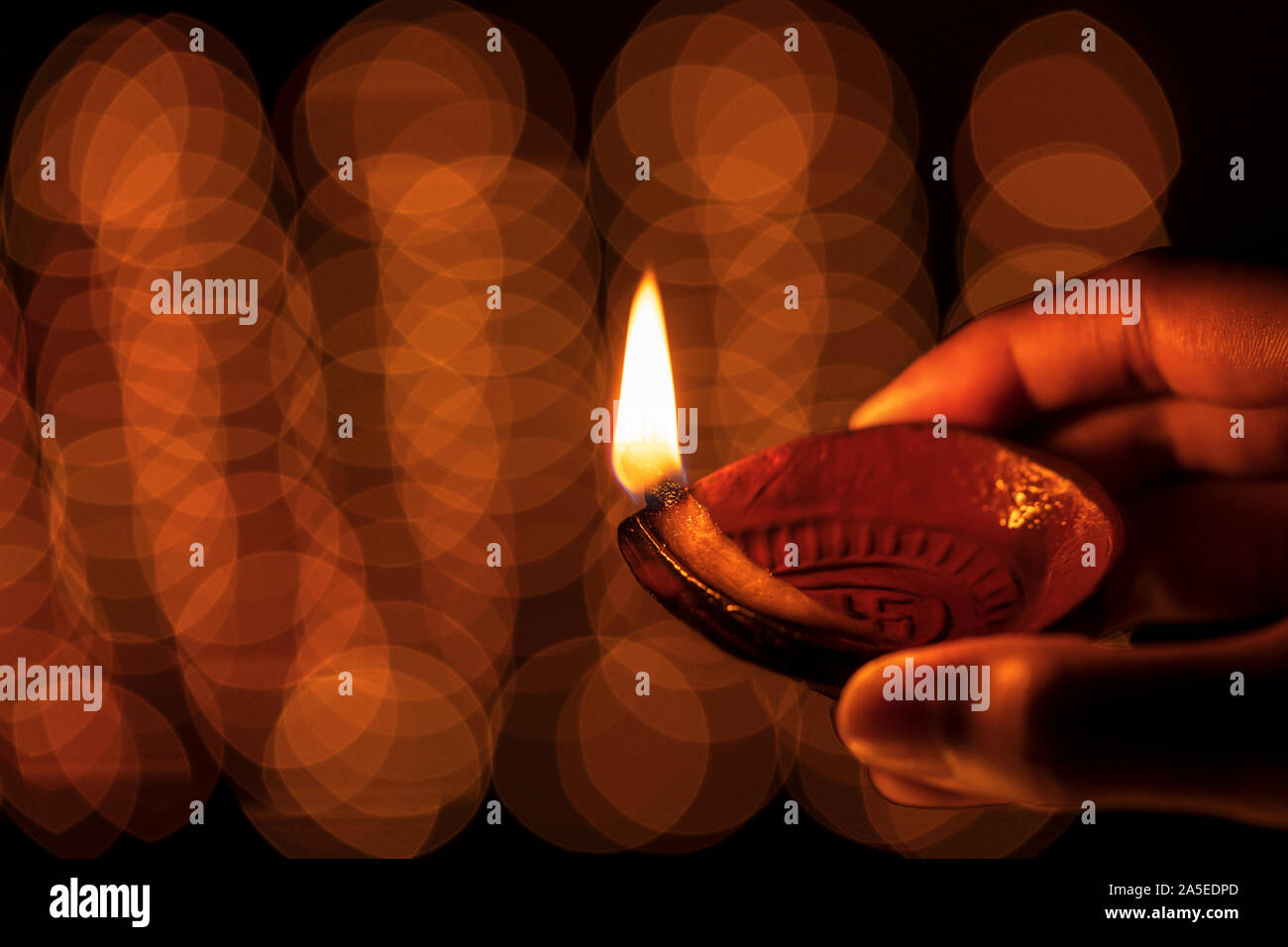 Felice Diwali - Femmina mano azienda Diya argilla olio lampada di notte, tempio con bokeh di luce. Magazzino immagine di sfondo per la decorazione di festa, rituali. Foto Stock