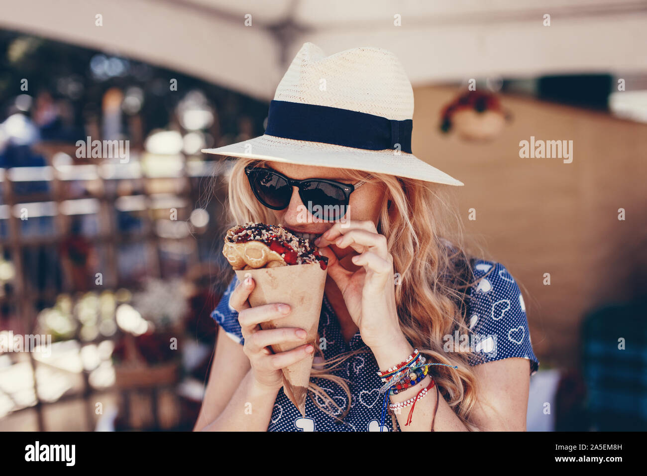 Giovane donna bionda mangiare waffle bolla al festival di fragola Foto Stock