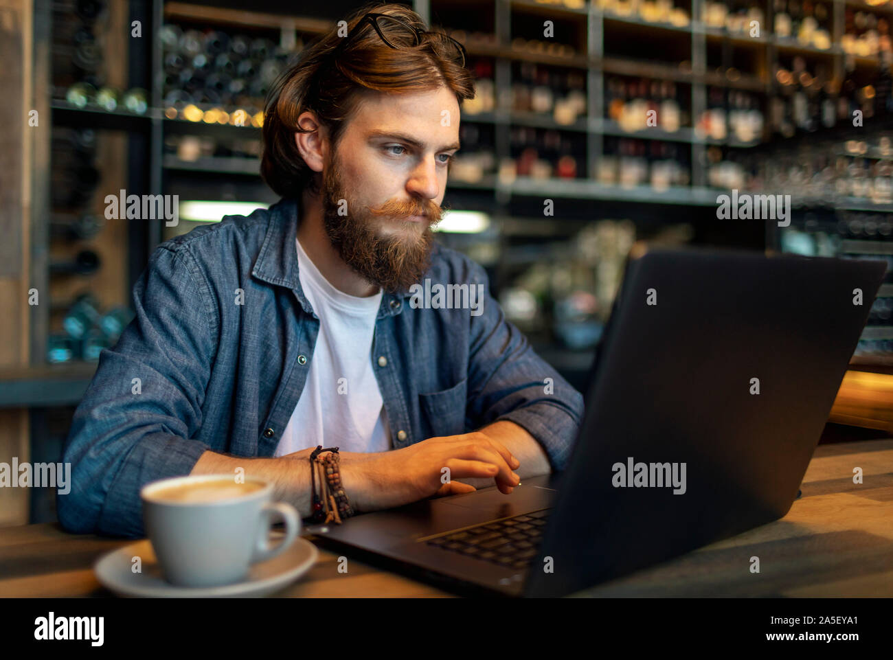 Concentrato di giovane imprenditore barbuto lavorando da un computer portatile in un cafe Foto Stock